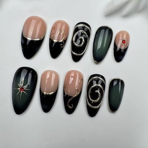 May include: Set of ten false nails with a black and green ombre design. Some nails feature a gold swirl design, others have a gold accent, and one has a red rhinestone.