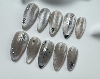 May include: Set of ten silver glitter oval-shaped press-on nails with silver star accents.
