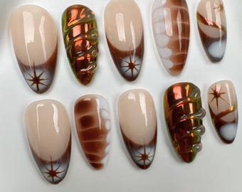May include: Set of ten false nails with a brown and white swirl design. The nails have a glossy finish and feature a starburst design on the tips.