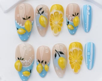 Uñas postizas con diseño de limón veraniego, lindas uñas amarillas con diseño de limón, uñas azules con punta francesa.