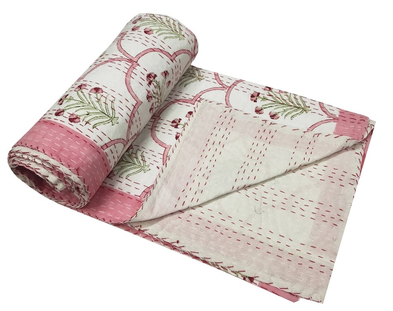 May include: A white and pink kantha quilt with a floral pattern. The quilt is hand-stitched and has a traditional Indian design.