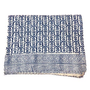 May include: A blue and white cotton quilt with a geometric pattern. The quilt is folded and has a fringed edge.