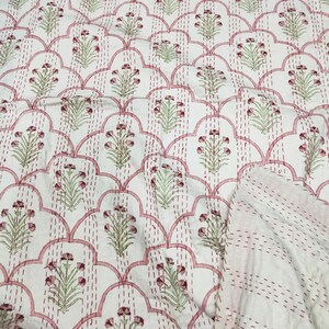 May include: White cotton fabric with a pink and green floral pattern. The fabric is quilted with a pink thread and has a scalloped design.