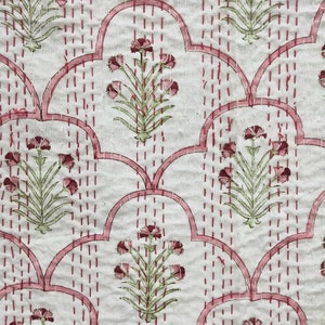 May include: White fabric with a pink and green floral pattern. The fabric has a quilted design with pink stitching.