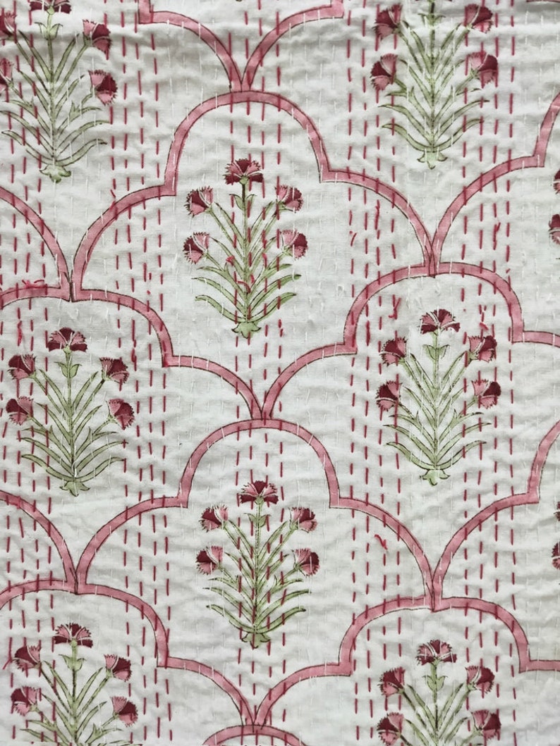 May include: White fabric with a pink and green floral pattern. The fabric has a quilted design with pink stitching.