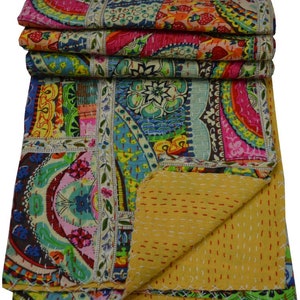 May include: A colorful kantha quilt with a patchwork design. The quilt is made of cotton and has a yellow backing. The quilt is folded in half and the front side is visible.