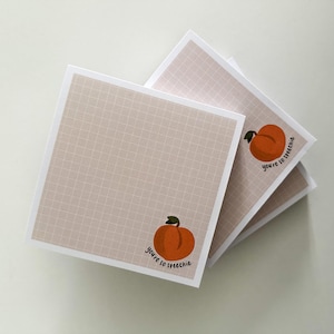 May include: Square notepads with a peach illustration and the text "you're so speeche" in a handwritten style. The notepads have a beige grid pattern background and white borders. The peaches are orange with green leaves.