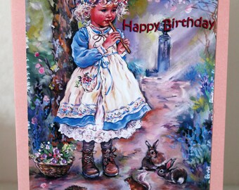 Op de afbeelding: Een roze verjaardagskaart met een afbeelding van een jong meisje in een witte jurk en een blauw jasje dat fluit speelt in een bosrijke omgeving. De kaart zegt "Happy Birthday" en "To our beautiful Granddaughter".