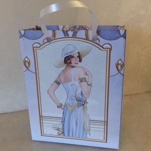 May include: A white gift bag with a white ribbon handle. The bag features a vintage illustration of a woman in a white dress and hat.