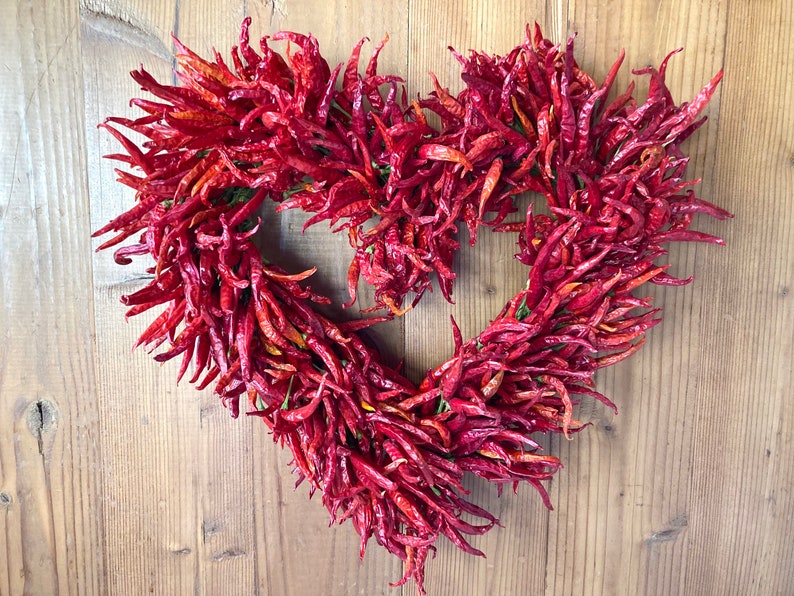 K&ouml;nnte beinhalten: Ein herzf&ouml;rmiger Kranz aus getrockneten roten Chilischoten.