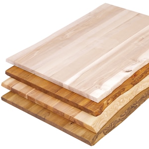 May include: Four pieces of wood stacked on top of each other. The top piece is a light wood with a smooth surface. The other three pieces are darker wood with a more textured surface.