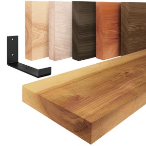 Può includere: Un set di cinque mensole in legno in diverse finiture di legno, tra cui naturale, sbiancato, marrone scuro, marrone rossiccio e legno scuro. Le mensole sono realizzate in legno massello e hanno un aspetto rustico. Il set include anche due staffe in metallo nero per il montaggio delle mensole.
