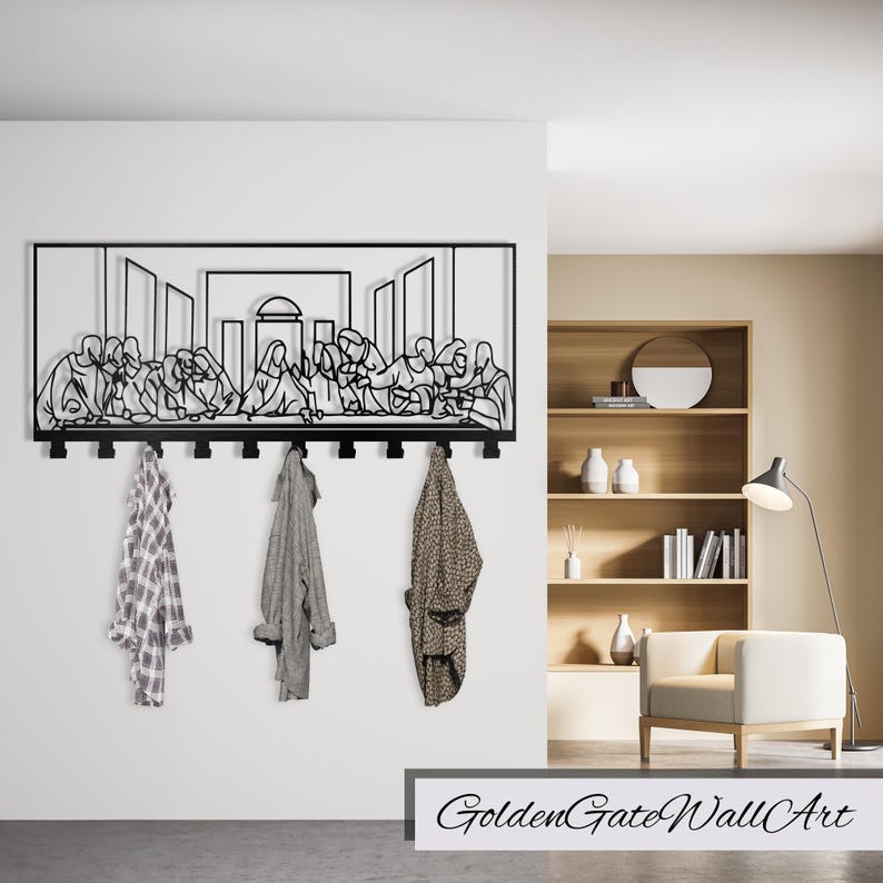 Puede incluir: Arte de pared de metal negro que representa La &Uacute;ltima Cena con un perchero debajo. El arte est&aacute; montado en una pared blanca con una estanter&iacute;a de madera y una silla en el fondo.