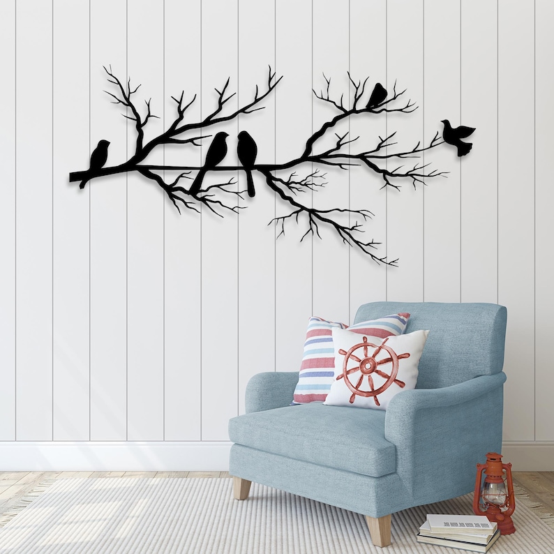 May include: A black metal wall art piece depicting a tree branch with several birds perched on it. The birds are in silhouette against a white wall. The artwork is a decorative element for a home.
