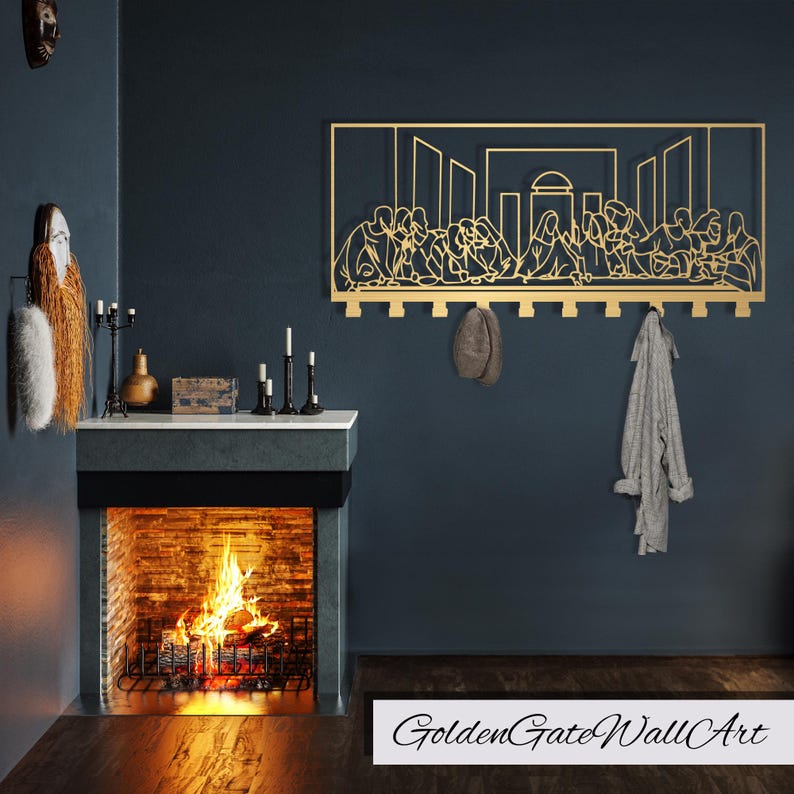 Puede incluir: Una obra de arte de pared de metal dorado que representa la &Uacute;ltima Cena con un perchero debajo. La obra est&aacute; montada en una pared azul oscuro con una chimenea debajo. La chimenea tiene un marco de ladrillo y un fuego ardiendo en su interior.