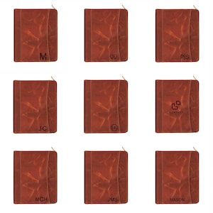 May include: Nine brown leather journals with gold zippers. Each journal has a unique design, including initials like "M", "S", "P/S", "J/C", "L/B", and "JMS", along with a company logo and the name "MASON".