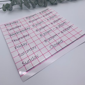 May include: A white sheet of paper with a grid pattern and black text listing business hours. The hours are listed for each day of the week, Monday through Sunday. The hours are 8:30am to 4:30pm, except for Sunday, which is closed.