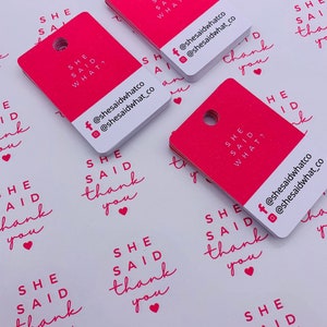 K&ouml;nnte beinhalten: Rosa und wei&szlig;e quadratische Etiketten mit dem Text "She Said" und "She Said What?" mit Social-Media-Handles f&uuml;r @shesaidwhatco. Die Etiketten haben ein Loch in der oberen Ecke.