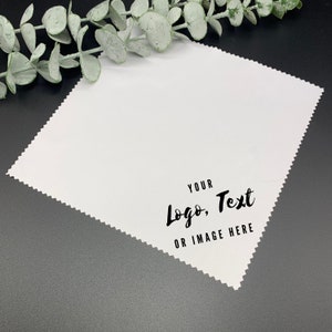 May include: White microfiber cleaning cloth with a jagged edge. The text "YOUR Logo, Text OR IMAGE HERE" is printed in black on the cloth.
