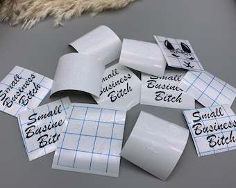 Könnte beinhalten: Eine Sammlung weißer Vinyl-Aufkleber mit dem Text "Small Business Bitch" in schwarzer Schrift. Die Aufkleber befinden sich auf einer weißen, karierten Unterlage.