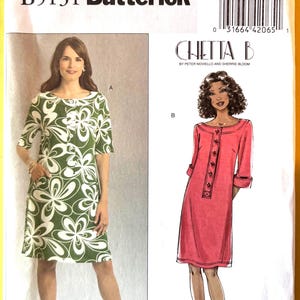May include: Butterick sewing pattern B5131 featuring two dress designs. One dress is green with white floral print, the other is a coral-colored dress with button details. The pattern includes sizes 16-22.