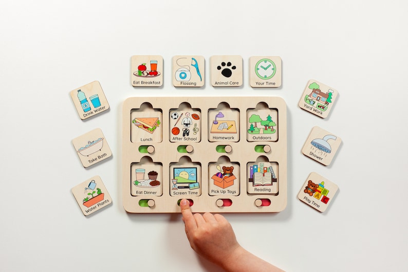 Puede incluir: Un tablero de tareas de madera con ocho ranuras que contienen fichas cuadradas extra&iacute;bles. Cada ficha presenta una ilustraci&oacute;n colorida y texto para tareas diarias como Eat Breakfast, Flossing, Animal Care, Your Time, Drink Water, Take Bath, Water Plants, Lunch, After School, Homework, Outdoors, Eat Dinner, Screen Time, Pick Up Toys, Reading, Yard Work, Shower y Play Time.