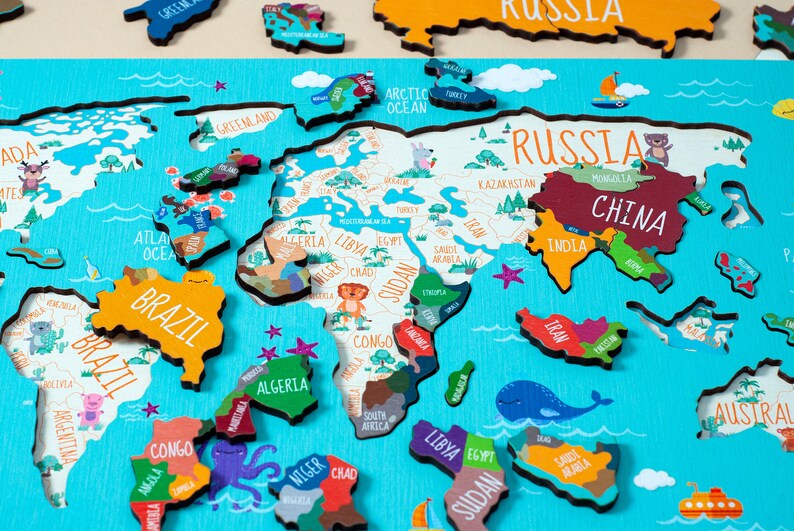 May include: A colorful wooden world map puzzle with names of countries and continents. The puzzle pieces are shaped like the continents and are arranged on a blue background. The puzzle is made of wood and has a light brown finish.