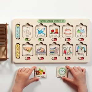 Puede incluir: Un tablero de responsabilidades diarias de madera clara con diez ranuras, iconos de tareas coloridos y etiquetas como Toilet, Brush Teeth, Eat Breakfast, Vitamins, Get Dressed, Lunch, Do The Dishes, Fold Laundry, Cleaning y Reading.