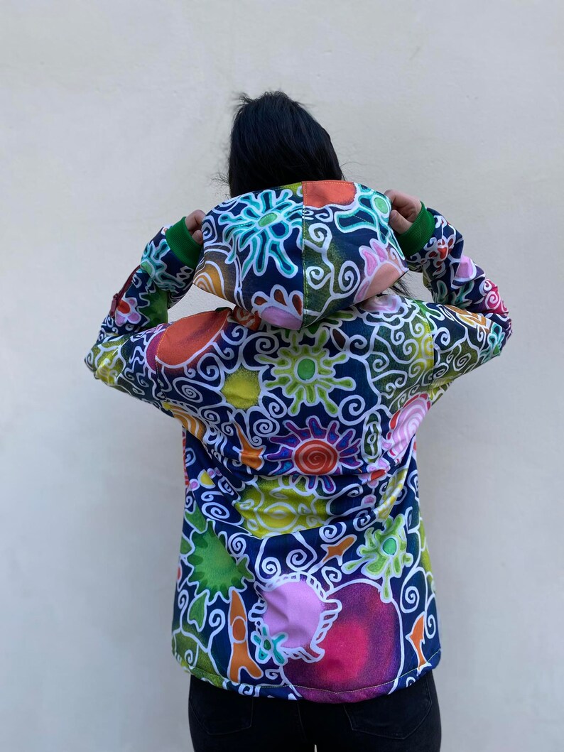 May include: A colourful hooded jacket with a swirling, abstract pattern in shades of blue, green, orange, pink, and yellow. The jacket has a zip closure and a drawstring hood.