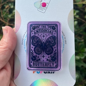 May include: Purple and black phone grip with a butterfly design and the text "The Antisocial Butterfly".