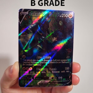 Op de afbeelding: Een holografische Pokemon-verzamelkaart met Lucario V, een blauw en zwart Pokemon met gloeiende ogen. De kaart heeft een zwarte achtergrond met groene en rode accenten. De tekst op de kaart luidt "Lucario V, HP 210, Aura Sphere, 40, Beatdown Smash, 180".
