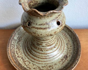 May include: A brown and green ceramic vase with a scalloped rim and a matching plate. The vase has a series of holes around the middle.