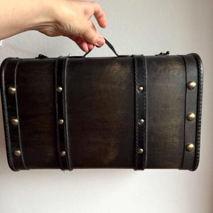 Vintage houten decoratieve koffer. Donkerbruine opbergkist met kunstleren handvat en metalen sloten. Retro middelgrote afgeronde rechthoekige stam.