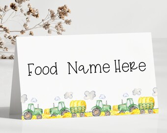 May include: A white folded table card with the text "Food Name Here". The bottom of the card features a watercolor illustration of green tractors, hay bales, and yellow fields. The card measures 10.16 x 6.35 cm.