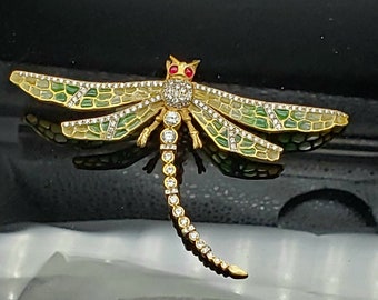 May include: A gold dragonfly brooch with green enamel wings and clear rhinestones. The dragonfly has red eyes.