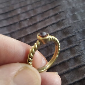 May include: A gold ring with a brown gemstone set in a twisted band.