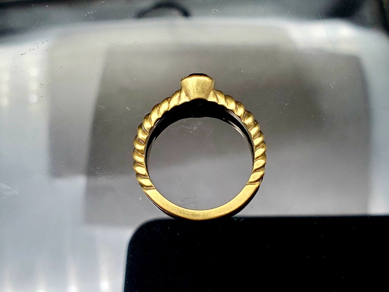 May include: A gold ring with a twisted band design. The ring is simple and elegant.