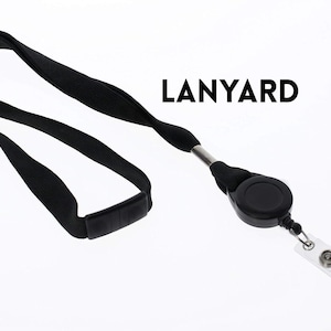 May include: Black lanyard with a retractable reel and a clear plastic badge holder. The word "LANYARD" is printed in black. The lanyard is made of a soft, woven material and is designed to be worn around the neck.