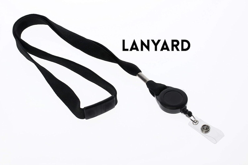 May include: Black lanyard with a retractable reel and a clear plastic badge holder. The word "LANYARD" is printed in black. The lanyard is made of a soft, woven material and is designed to be worn around the neck.