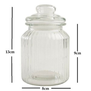 May include: Clear glass jar with a lid, 13 inches tall, 9 inches wide, and 8 inches in diameter. The jar has vertical ridges.