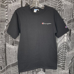May include: Black short-sleeved t-shirt with a small white Champion logo on the front. The logo is embroidered and has a red 'C'.