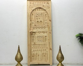 Puede incluir: Una puerta de madera tallada con intrincados patrones geométricos y un diseño tradicional marroquí. La puerta está hecha de madera clara y tiene un acabado natural.