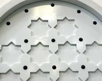 May include: White arched door with a geometric pattern of eight-pointed stars. The door is decorated with black metal accents.