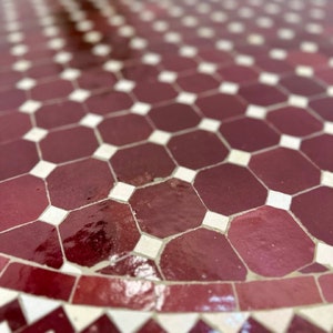 May include: Close-up of a burgundy and white mosaic tile tabletop. The tiles are arranged in a geometric pattern.