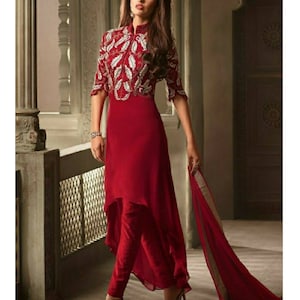 May include: A red dress with a high neck and a white embroidered design. The dress has a high-low hemline and is paired with red pants.