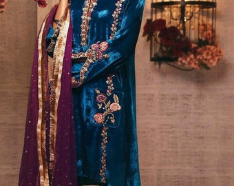 Könnte beinhalten: Eine tealblaue Samt-Tunika mit goldenen und silbernen Stickereien und floralen Verzierungen. Die Tunika wird mit einem lilafarbenen, durchsichtigen Dupatta mit goldenen Verzierungen kombiniert.