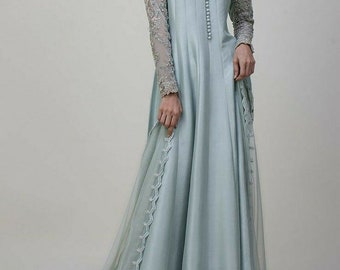 Könnte beinhalten: Ein hellblaues Maxikleid mit einem langen, fließenden Rock und einem taillierten Oberteil. Das Kleid hat einen runden Ausschnitt und lange Ärmel mit aufwendigen Stickereien. Das Kleid wird mit einem passenden, durchsichtigen Dupatta mit besticktem Saum kombiniert.