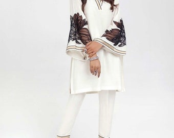 May include: A white tunic top with black floral embroidery on the sleeves. The top has a V-neckline and is paired with white trousers.