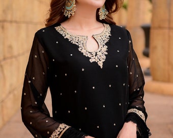 May include: A black sheer long-sleeved dress with gold embroidery and sequins. The dress has a round neckline with a keyhole opening and a fitted silhouette.