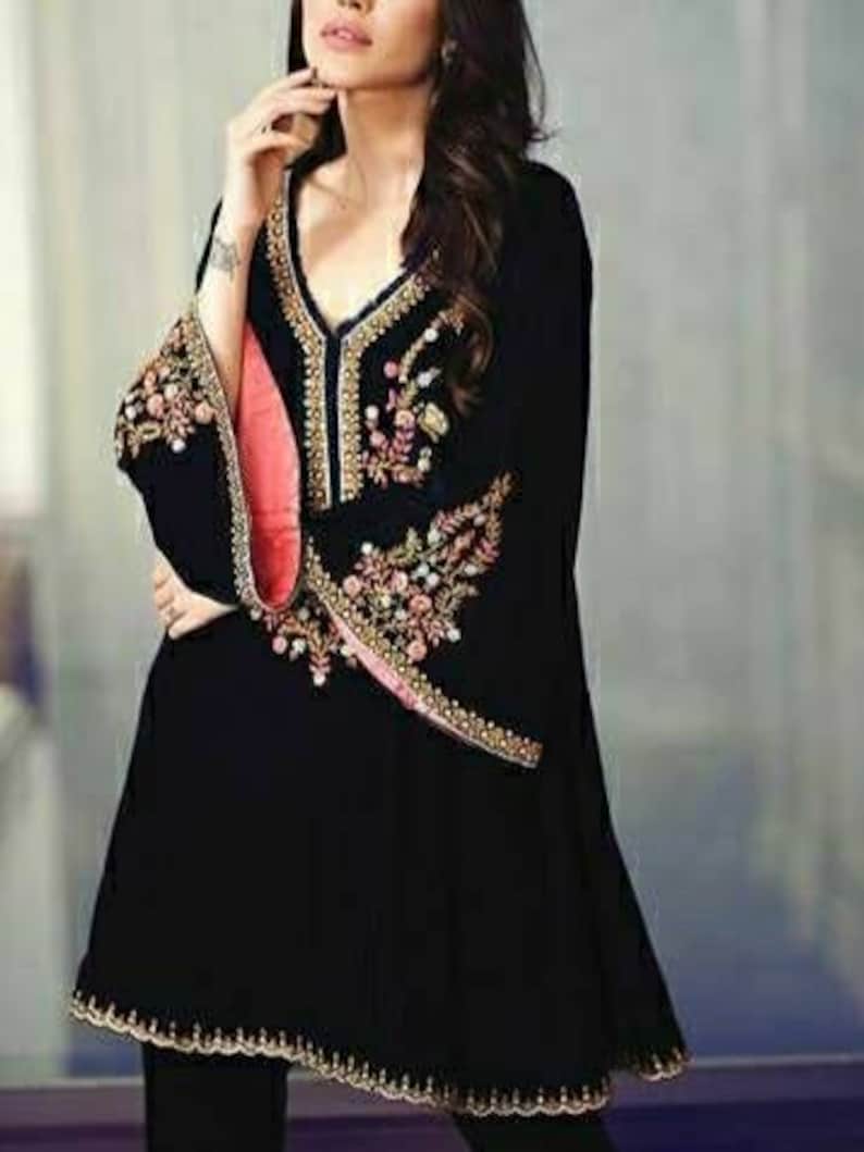 May include: Black tunic with ornate embroidery in gold, pink, and green. The tunic features a V-neck and flared sleeves with a scalloped hem. The sleeves have a pink lining. The garment is a stylish piece of clothing.